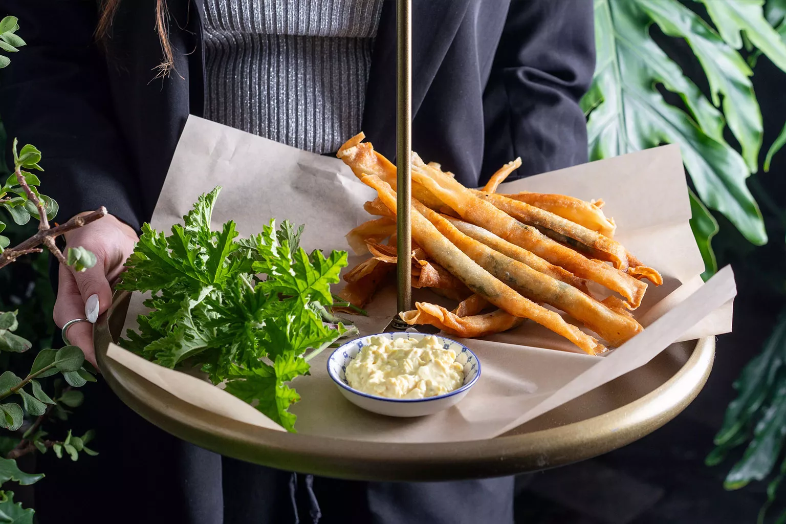 טעימות השף מגש הגשה עם מאפי פילו מטוגנים וזהובים, מוגשים לצד רוטב קרמי ועשבי תיבול טריים. צילום תקריב המדגיש פריכות, צבע והגשה אלגנטית באירוח קולינרי.