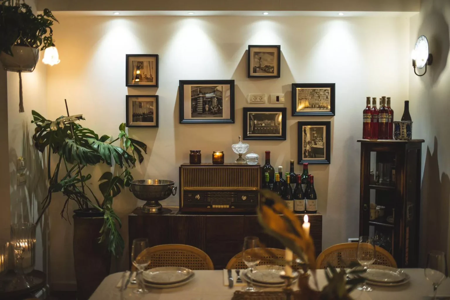 קיר מעוצב עם תמונות, רהיטי וינטג׳ ובקבוקי יין בחלל האירוח