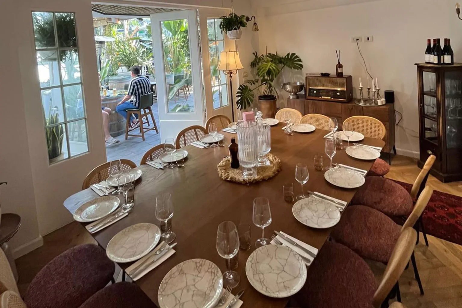 שולחן עץ גדול ערוך לאירוע עם יציאה לחצר בבית השף