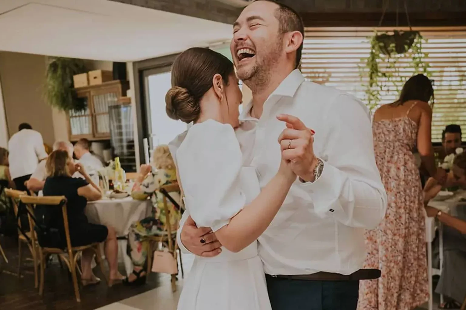 זוג רוקד בחתונה בבית השף בחלל פנימי עם אורחים סביב שולחנות